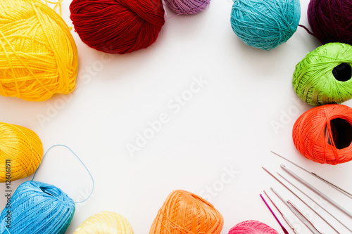 Colorful threads and knitting accessories frame, free space. Bright balls of yarn with needles and crochets on white background, copy space for text. Leisure, handiwork, hobby concept