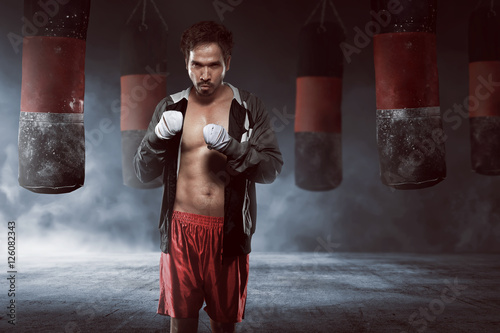 Young asian boxer man in a black robe with punching bag