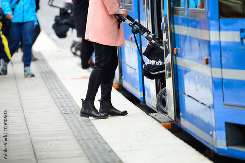 Woman with baby stroller entering tram