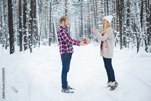 young man presents women Christmas gift in the forest