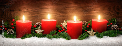 Advent Dekoration mit vier Kerzenflammen, Schnee, Tannenzweigen und Holz Hintergrund
