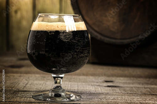 Russian Imperial Stout in snifter glass on wood background and b