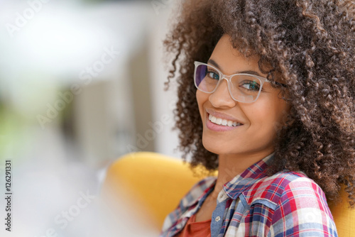 Attractive mixed race woman with eyeglasses relaxing in armchair