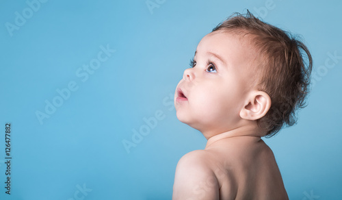 Cute Baby Girl Looking Up Against Vivid Blue Background