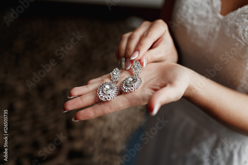 Wedding earrings on a bridal hand, bride's morning and jewelry accessories and decoration concept