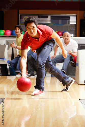 Man bowling, friends watching in the background