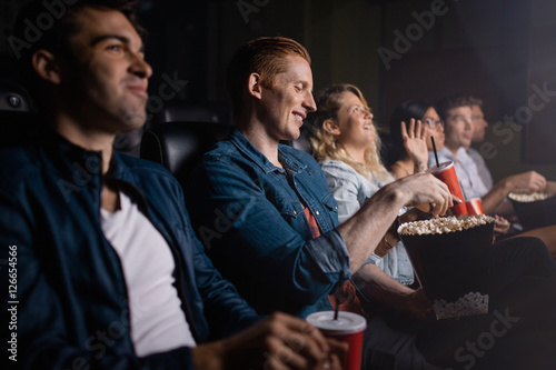 Young man with friends watching movie in cinema