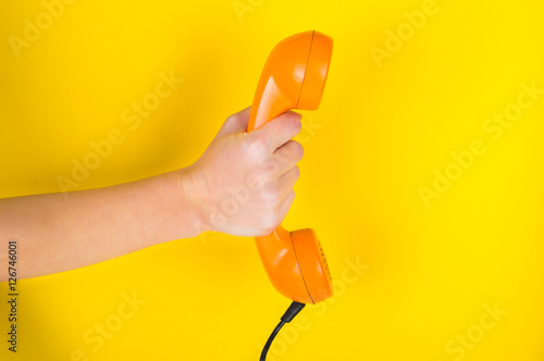 Orange handset in hand on a yellow background