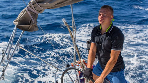A young man the skipper controls the movement of sailing yachts during the boat race. Travel and luxury stay.