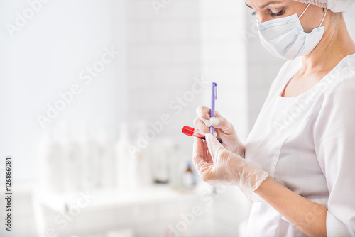 Experienced general practitioner writing on blood flask