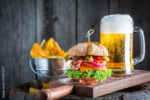 Beer and fresh hamburger made of beef, cheese and vegetables