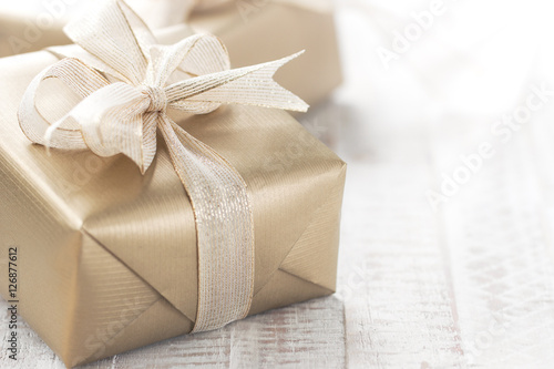 Golden gift boxes with beautiful ribbon and bow on a bright shin