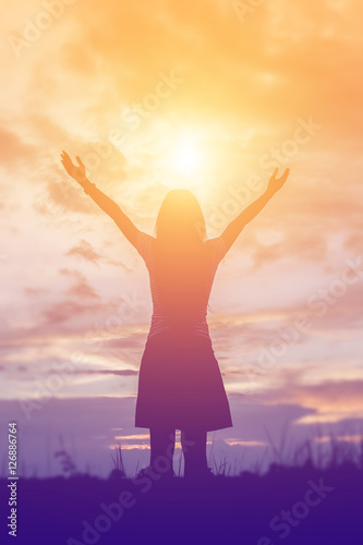 Silhouette of woman praying over beautiful sky background