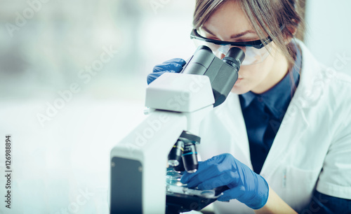 Young scientist looking through a microscope in a laboratory. Young scientist doing some research.