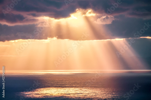 Rays of light after rain storm, seascape with sun reflections on water surface.