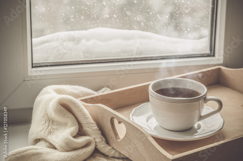 Tea on tray and sweater in from of snowing winter