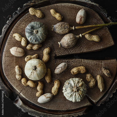 Grey pumpkin, nuts and dry poppy heads on wooden background