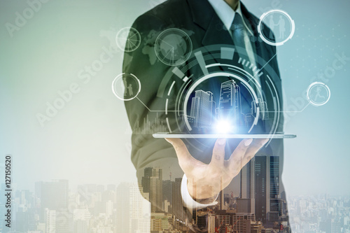 double exposure of smart city and a business person holding tablet pc