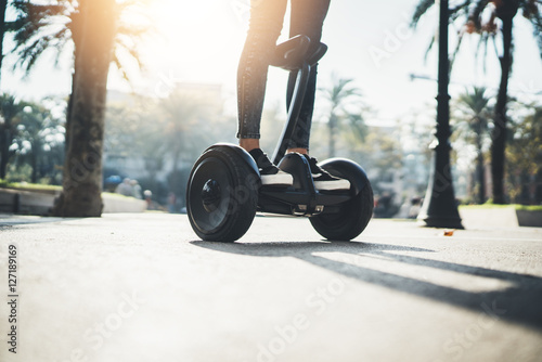 Young hipster girl driving on hoverboard at sunny park, active woman balancing on modern electric segway, alternative transport concept, ecology and environment concept, flare light