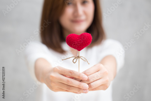 Giving love gift, Asian woman hand hold give beautiful red heart sweet loving symbol of take care or charity help to you.