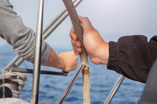 man hand holding a sailing vessel wheel.the sea in the background