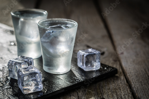 Vodka in shot glasses on rustic wood background