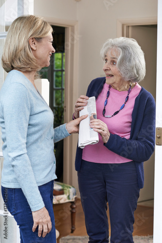 Woman Delivering Newspaper To Elderly Neighbour