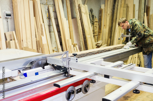 Carpenter working on woodworking machines with a circular saw