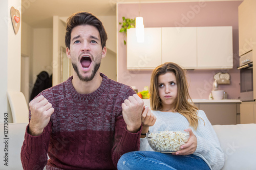 Bored girl watching the football game with her boyfriend