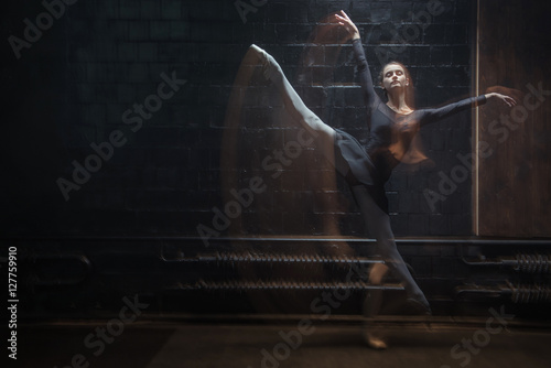 Young dancer jumping in front of the black wall