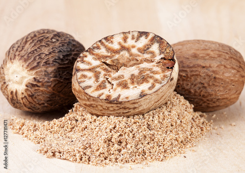 Nutmeg , whole and half on wooden plank, close up