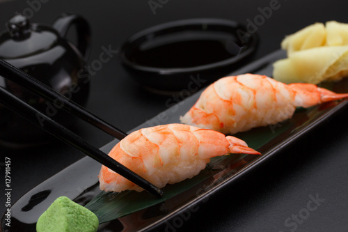 Shrimp sushi nigiri on a black plate over dark background