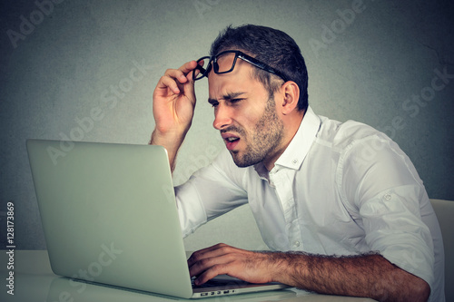 man with glasses having eyesight problems confused with laptop software