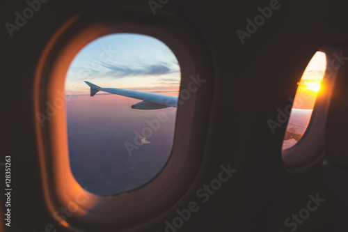 Sunset aerial view through airplane window over wings