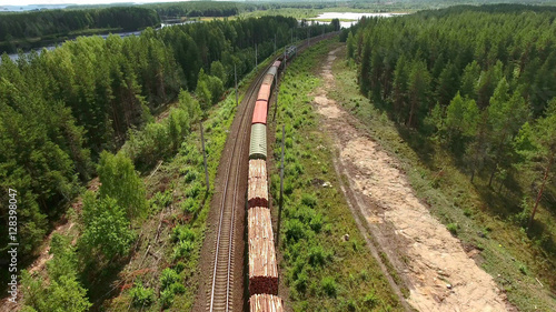 Cars of freight train passing to a distance at the double line railway in forests of Karelia, Russia. Aerial rear view