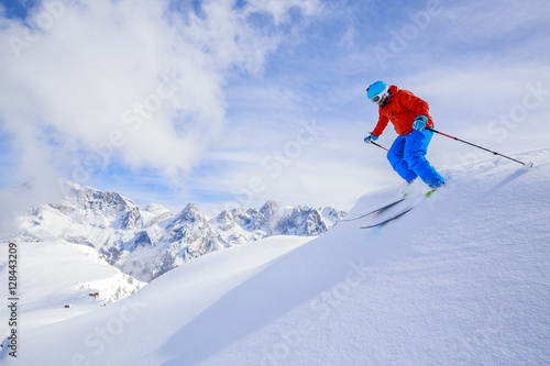 Skier skiing downhill in high mountains in fresh powder snow. Sa
