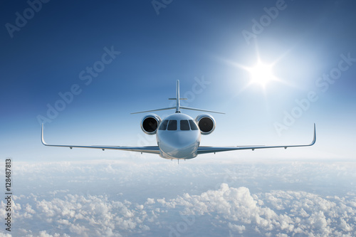 Private jet flying towards the camera with the sun in blue sky