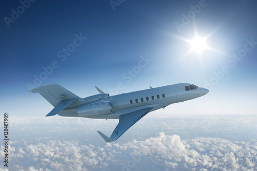 Private jet flying above the clouds with the sun in blue sky