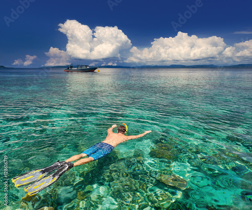 man snorkeling in clear tropical waters over coral reefs