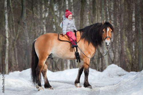 Horseback - child riding a horse. Horse and girl in winter.