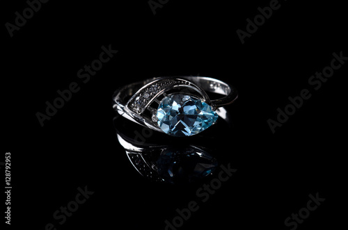 Silver ring with blue topaz isolated on a black background.