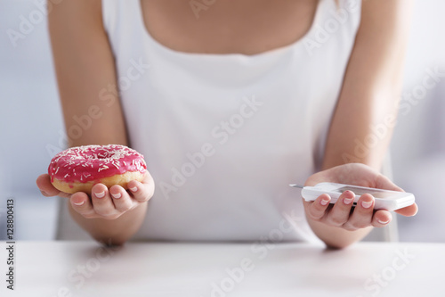 Woman with donut and blood sugar level at home