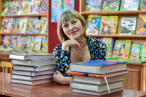 Information age/The girl - librarian talking on a smartphone on the background of bookshelves