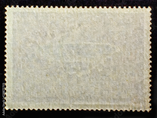 Old posted stamp reverse side with the edge of the sheet. Texture of paper.