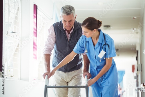 Nurse helping senior man with walking aid