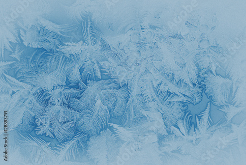 Blue frost pattern on a window glass in the winter (as an abstract winter background in subdued colors), retro style