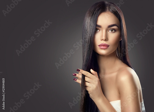 Beauty brunette model girl touching long healthy hair