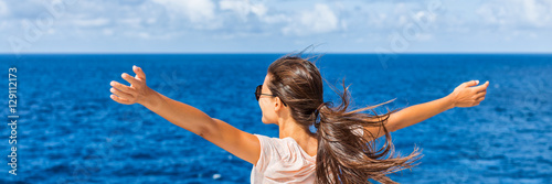 Happy freedom woman with open arms looking at blue sea horizon outdoors. Carefree person living a free life. Panorama horizontal banner crop for success and bliss concept.