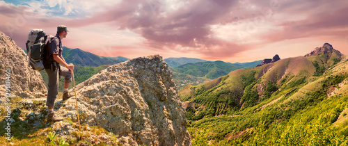 Hiker on the top enjoys mountains panorama landscape before sunrise