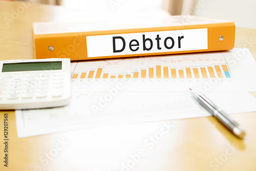 Orange binder debtor on desk in the office with calculator and